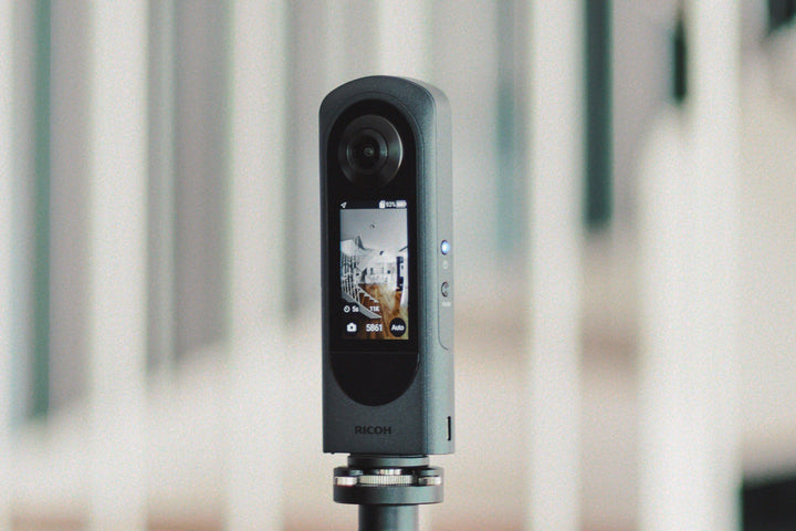 Caméra 360 Ricoh Theta noire fixée sur un trépied avec écran affichant la prise de vue.