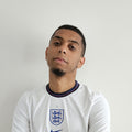 Homme portant un maillot de football blanc style équipe nationale sur fond neutre.