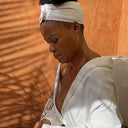 Femme en routine beauté avec bandeau de soin et peignoir dans une ambiance spa relaxante.