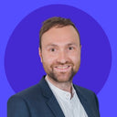 Photo de profil professionnelle d’un homme en costume sur fond bleu.