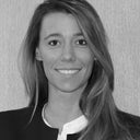 Portrait en noir et blanc d’une femme souriante en tenue professionnelle sur fond texturé.